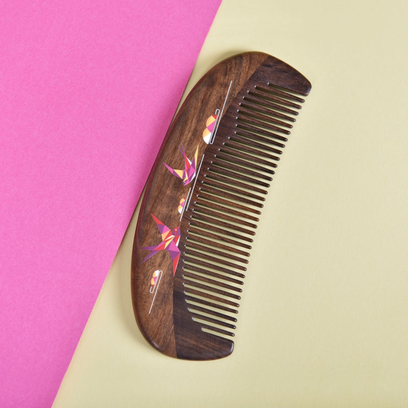 Wooden comb with floral design on a pink and beige background